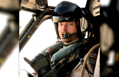 Male navy pilot in helicopter cockpit wearing helmet and flight suit