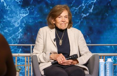 Sylvia Earle sits in front of large blue and white oceanic themed screen
