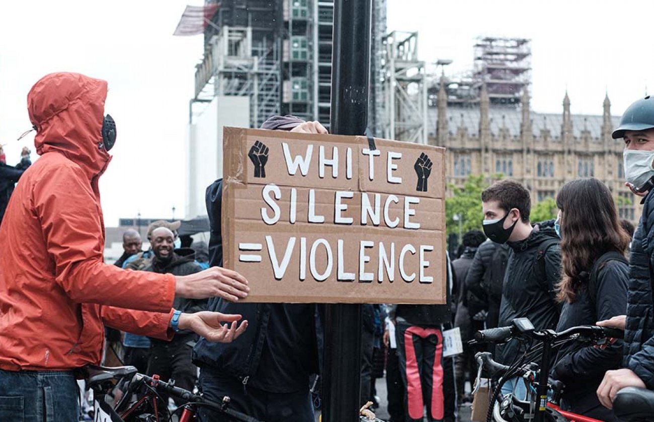 Photo of a crowd of people and a sign that reads "white silence = violence"