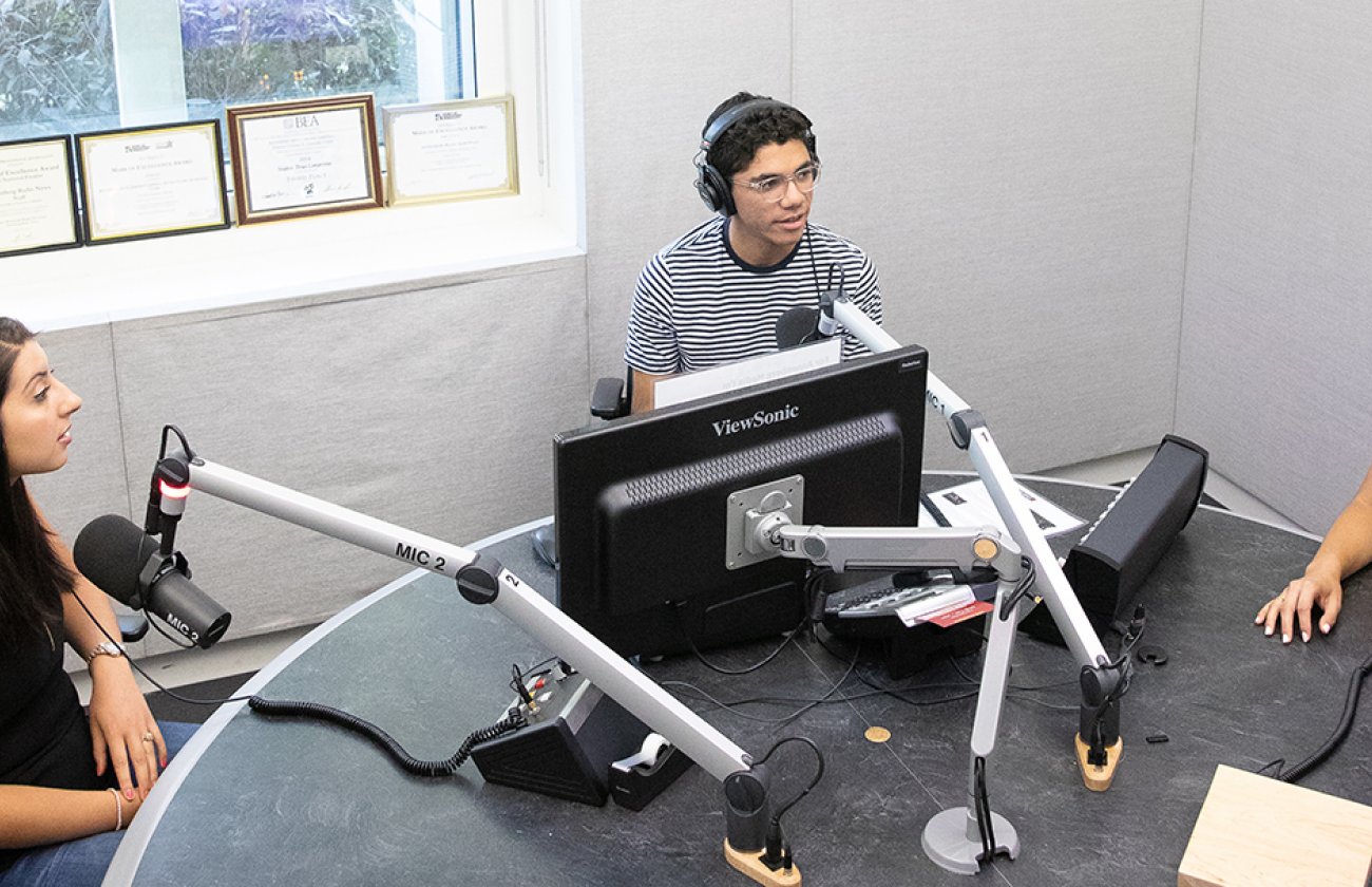 Photo of three people in a podcast studio