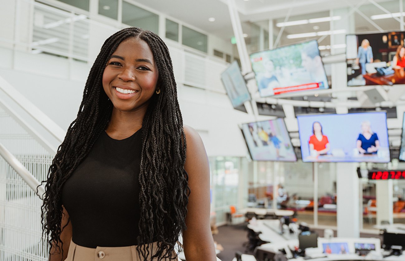 Young woman standing in front of the USC Annenberg Media Center media halo, smiling.