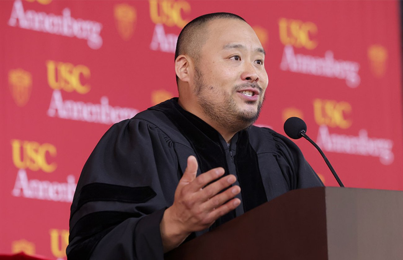 David Chang in graduation regalia address crowd in front of USC Annenberg banner