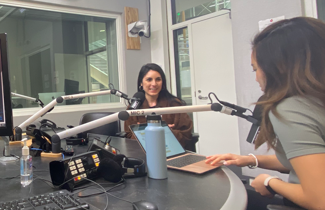 Two female college students converse in podcast studio