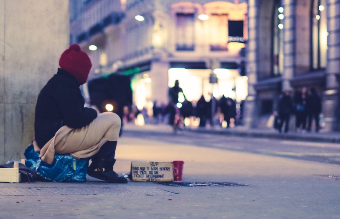 Photo of a homeless person on a busy street at nighttime