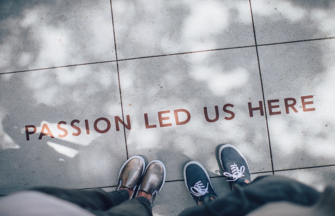 Photo of people standing next to words on the floor reading "passion led us here"