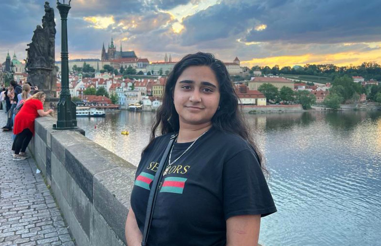 A woman with black hair, Raka Bhattacharyya, stands by a river on a bridge.