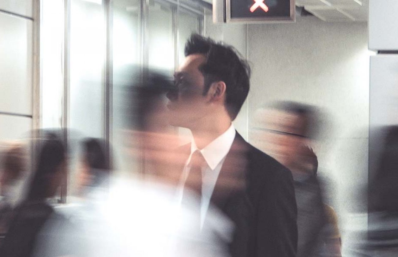 Photo of a person in business attire in focus with other people blurry around them