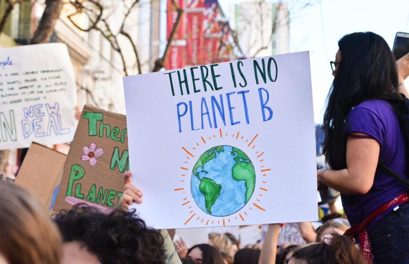 group of students demonstrating together and holding a sign that says there is no planet B