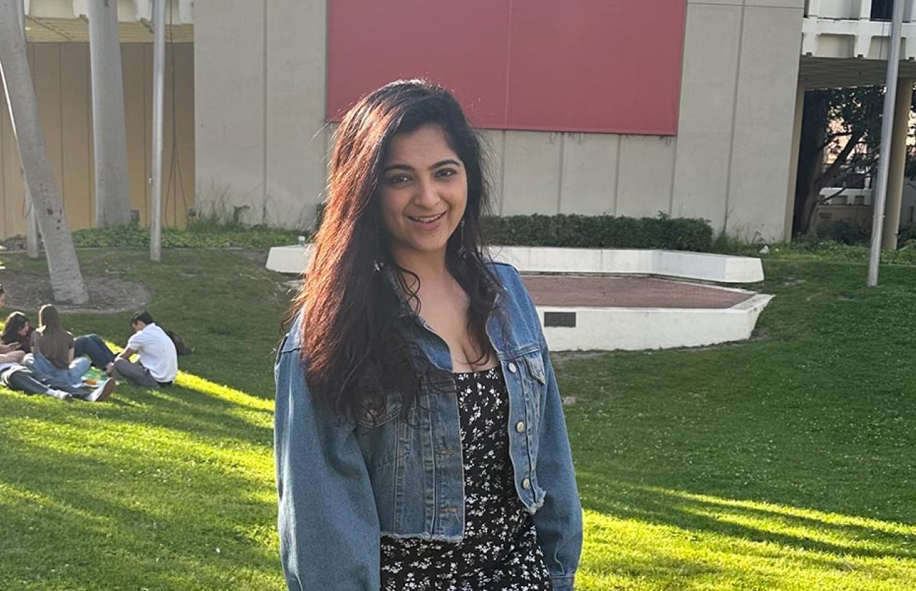 Woman standing outside on grass near a building. 