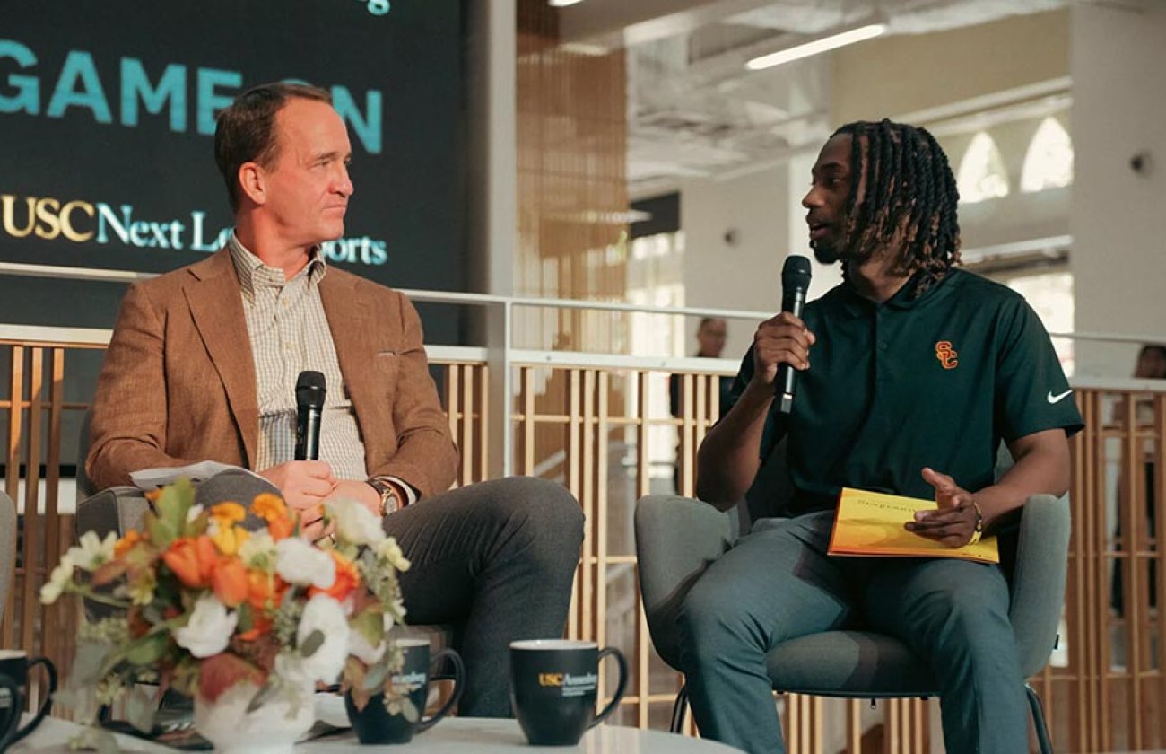 In the Wallis Annenberg Hall Forum, Peyton Manning, left, engages with student Elijah Patterson, right, who holds a mic and asks a question.