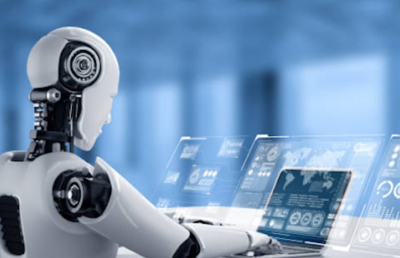 A robot typing on a laptop, sitting at a desk