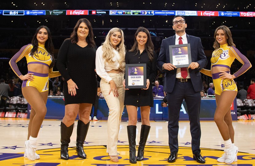 Jeanie Buss and daughter stand next to female and male college students with two laker cheerleaders at each end of group
