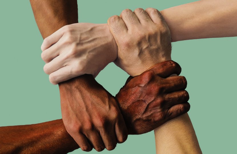 Four hands of different races grasp each other.