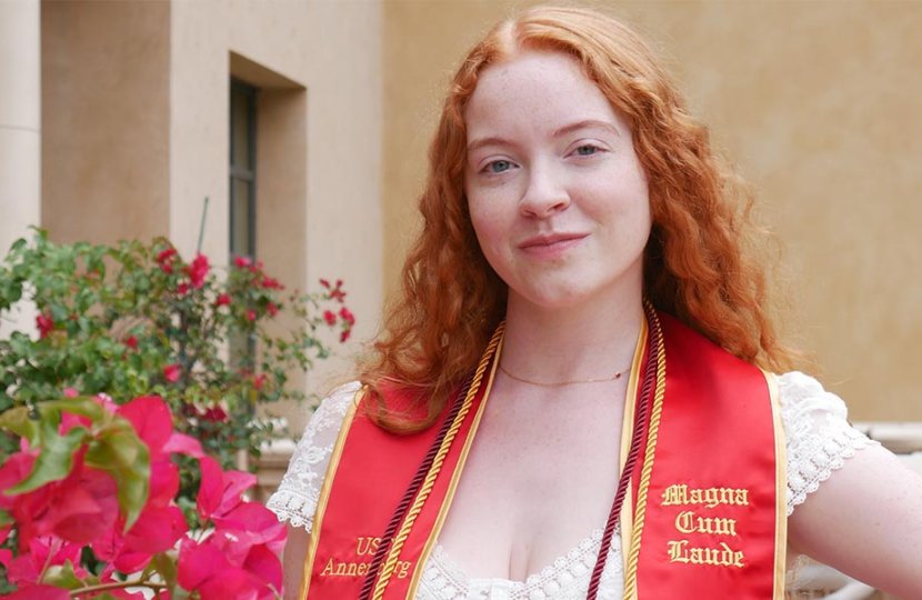 women with red hair wearing graduation stoll poses by flowers