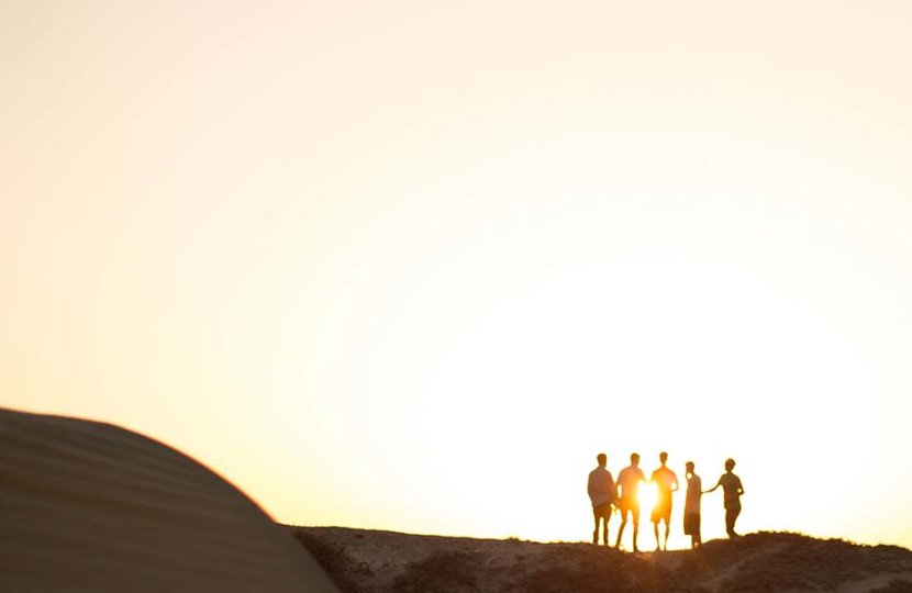 Photo of people standing with a sunset making them into silhouettes
