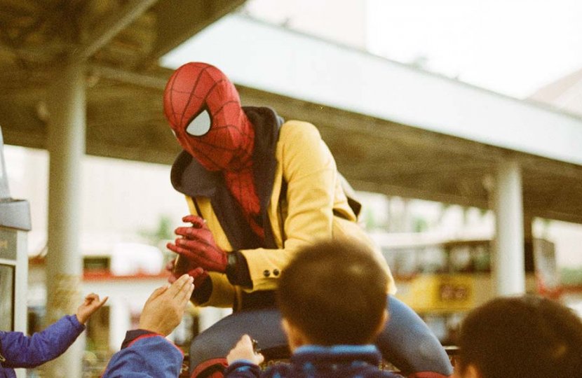 Photo of a person dressed like spiderman around a crowd