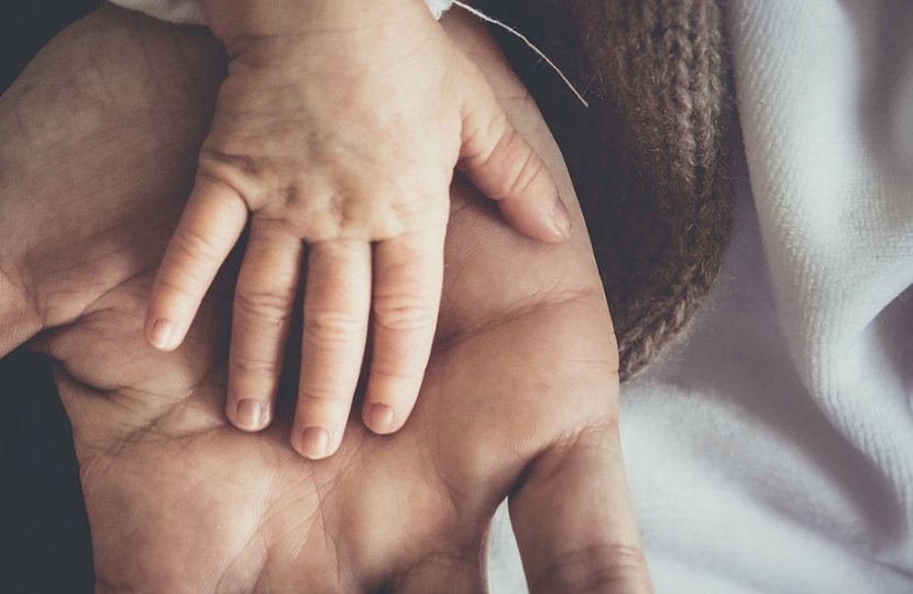 Photo of a baby's hand place on top of an adult's hand
