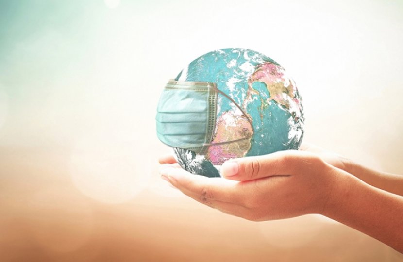 Image of a person holding a globe in their hands with a face mask on it