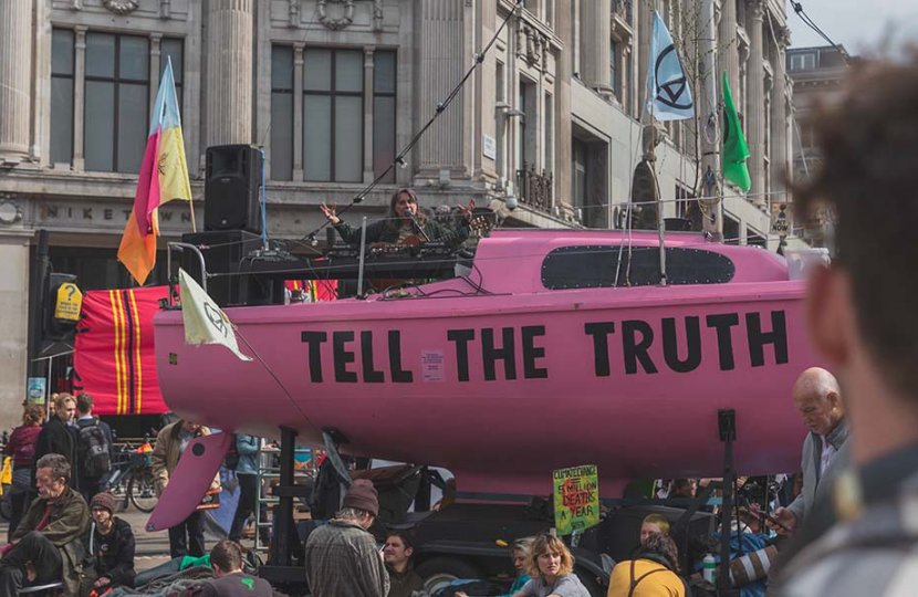 Photo of a pink blimp in a crowd of people that reads "tell the truth"