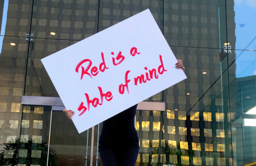 Photo of a person holding a sign that says "red is a state of mind"
