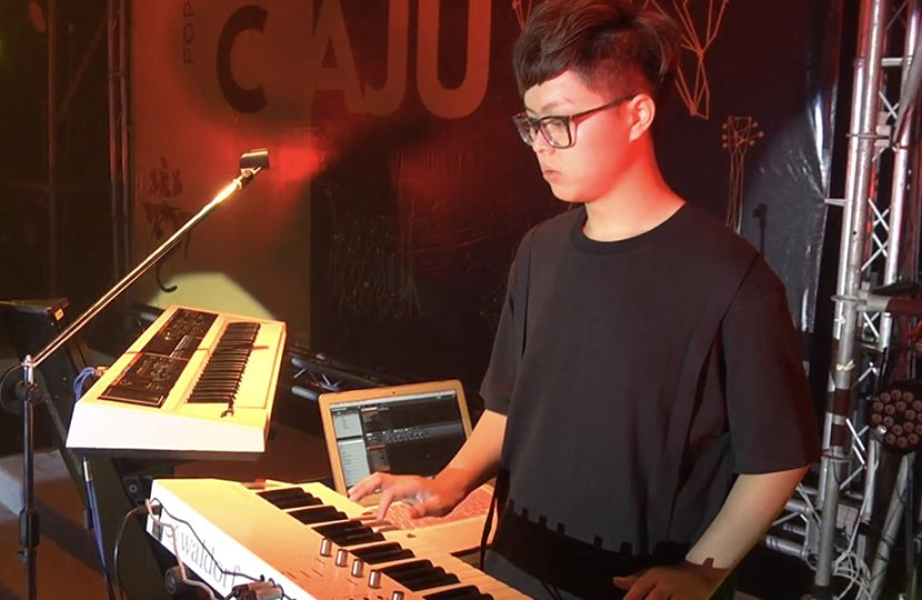 Male Asian man plays key board and DJs at night club