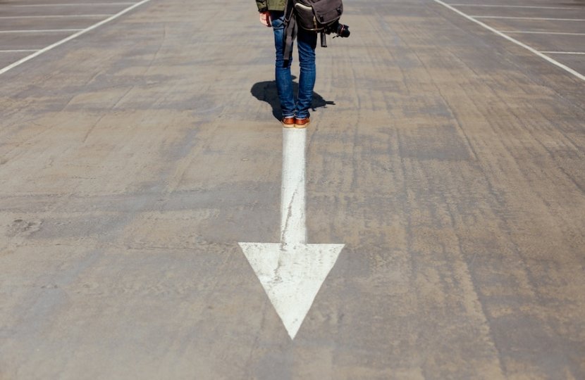 Photo of a person standing behind a white arrow on a street