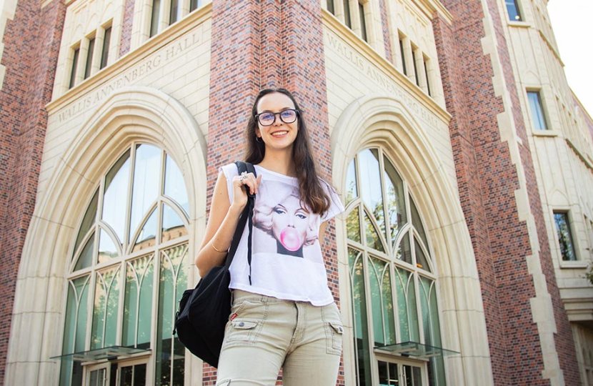 Italian college woman stands in front of USC Annenberg building wearing backpack