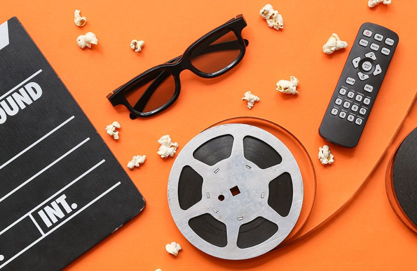 Film- and TV-related artifacts, such as a remote control, a spool of film, scattered popcorn, and a blank clapperboard, are scattered over an orange backdrop.