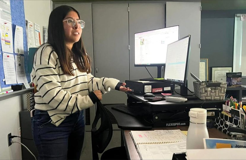 Wendy Chavez at the teacher's desk in a classroom.