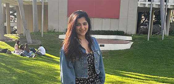 Woman standing outside on grass near a building.