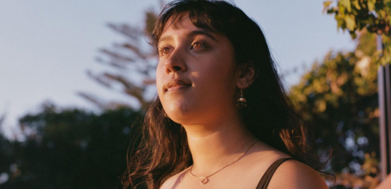 A close up portrait of a woman looking off camera as sunlight shines on her face.